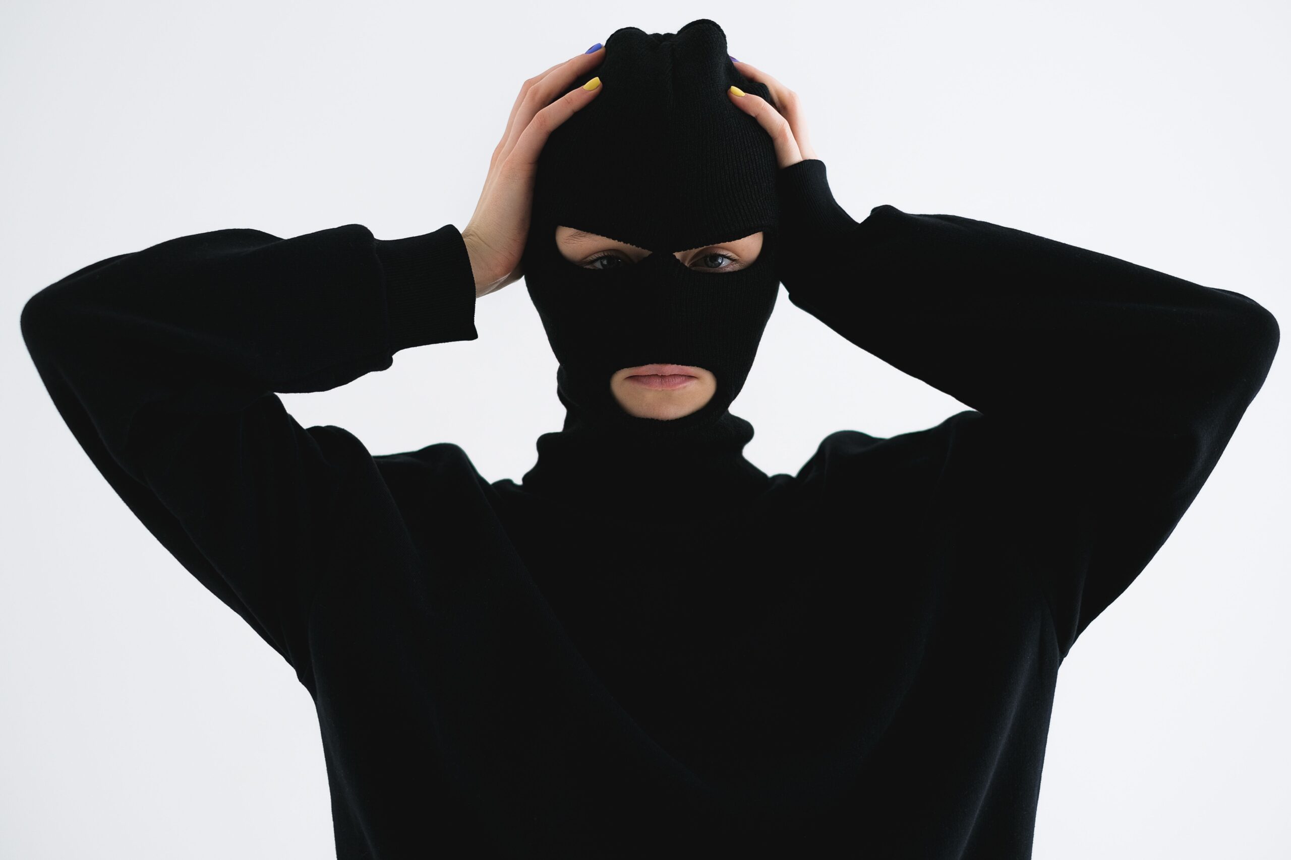 Man stands with black full face mask and a black long sleeve shirt